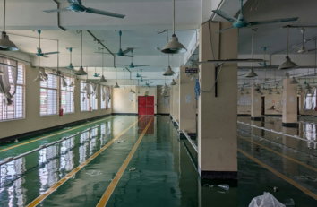 A large room with lots of windows and a ceiling fan