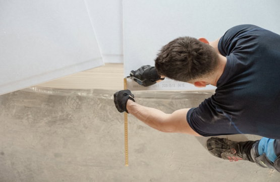 a man measuring a piece of wood with a measuring tape